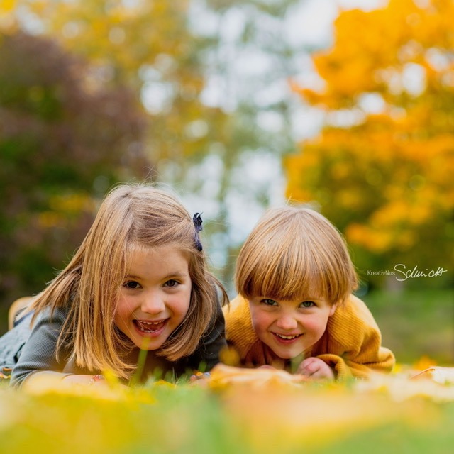 Kinder spielen im Herbstlaub bei Familienfotografie in Hannover