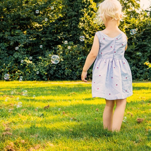 authentisches Kinderportrait mit Mädchen und Seifenblasen draußen in der sonnigen Natur von Familienfotografin KreativNus Schmidt Fotografie